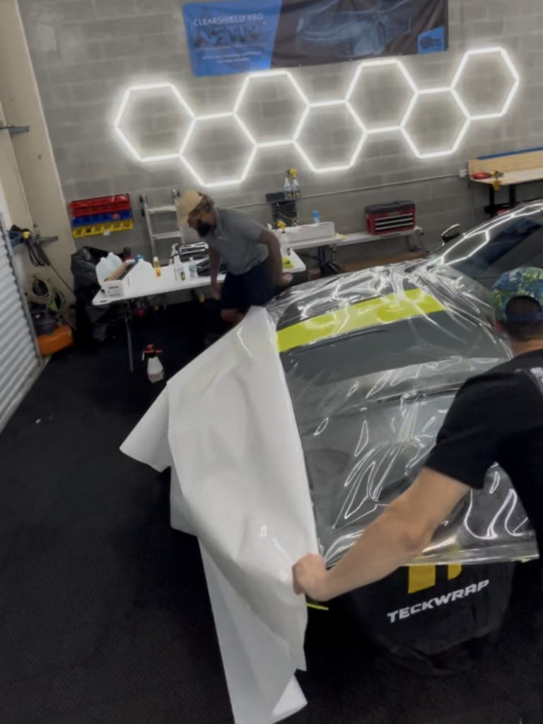 Clear paint protection film being installed on the front end of an Aston Martin DB11