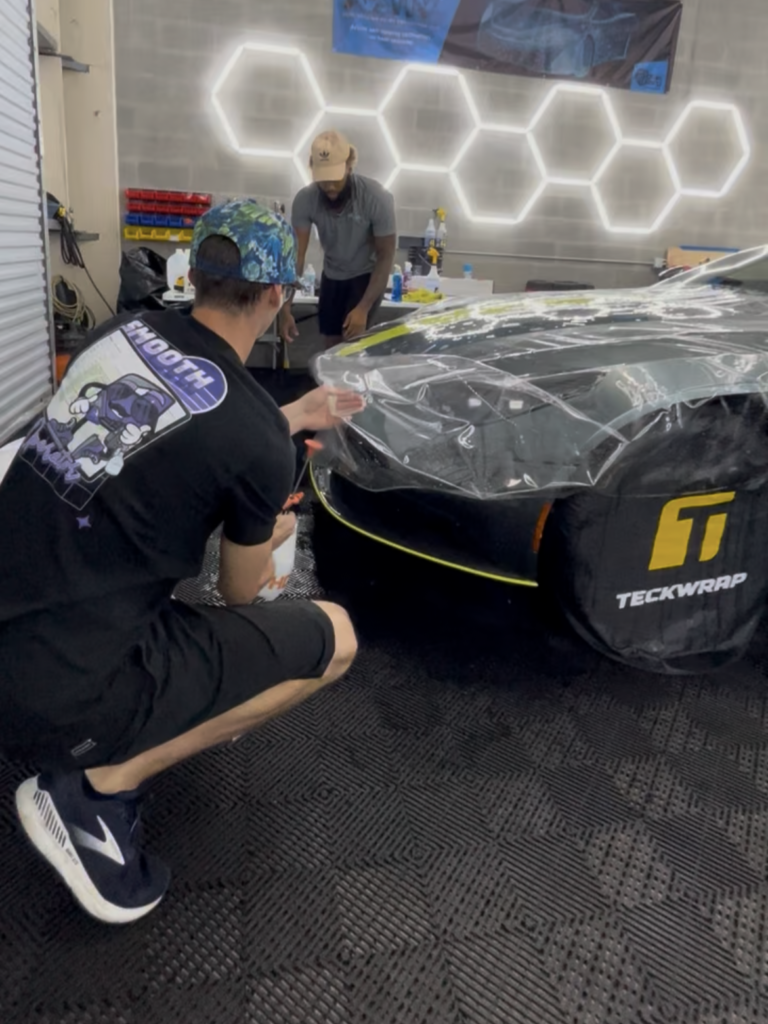 Installer applying paint protection film to the front end of an Aston Martin DB11