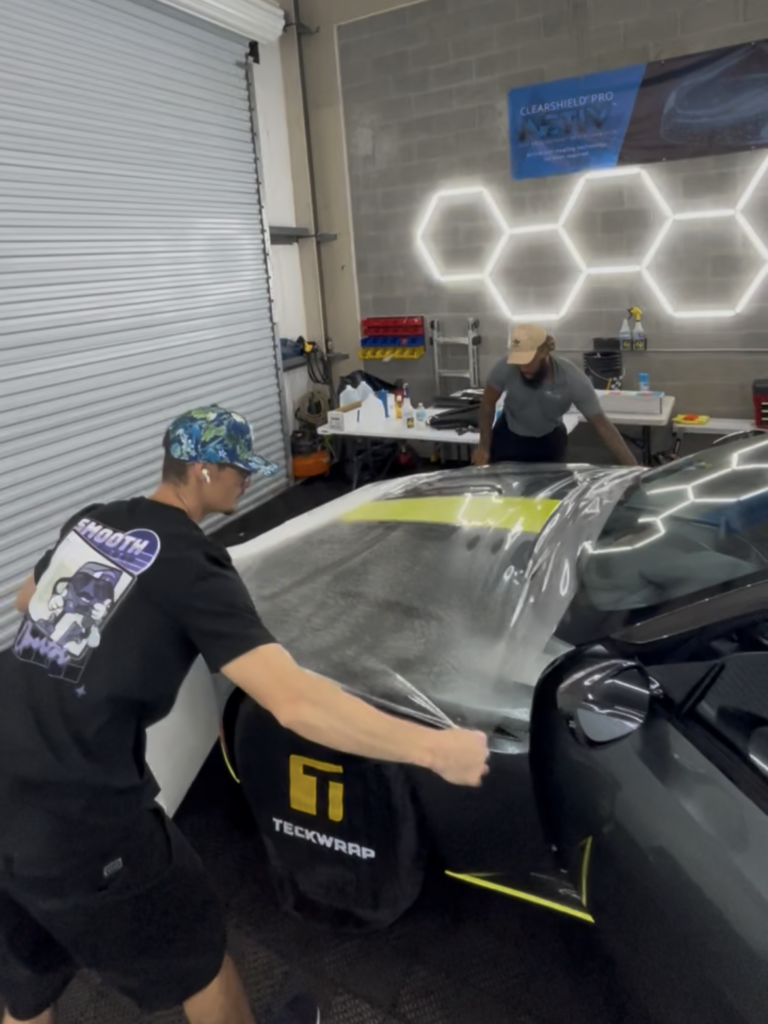 Paint protection film being installed on the hood of an Aston Martin DB11
