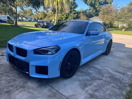 Blue BMW coupe with dark tinted windows, viewed from the front driver’s side.